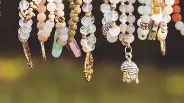 Beaded necklaces hanging outdoors in sunlight.