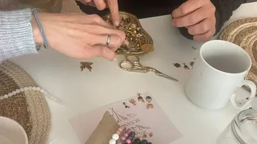Hands arranging jewelry on a table.