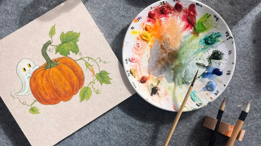 Paint palette beside ghost pumpkin drawing.
