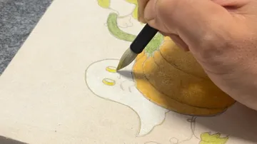 Hand drawing ghost and pumpkin on paper.