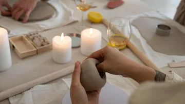 Hands molding clay on a table.