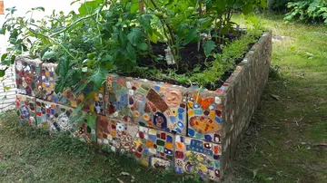 Mosaic planter with plants in a garden.
