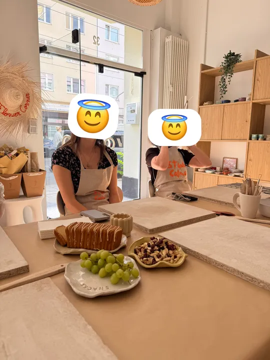 Zwei Personen sitzen am Tisch, Basteln und Snacks.