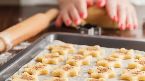 Cookies prepared on baking tray, hands roll dough.