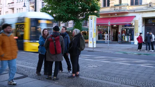 Menschen sprechen nahe einer fahrenden Straßenbahn, Stadtstraße.