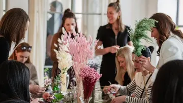 Leute arrangieren Blumen an einem Workshop-Tisch.