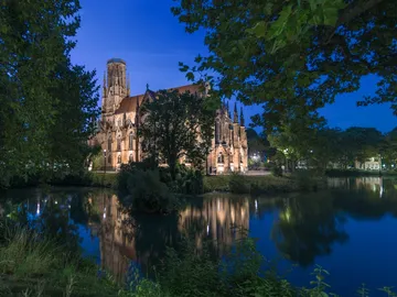 A church is reflected in calm water at night.
