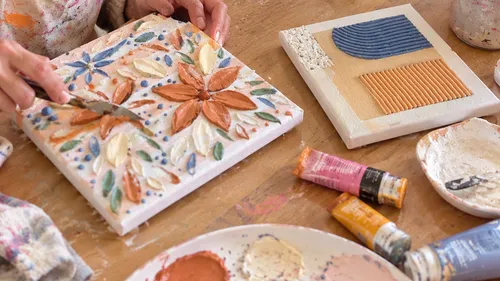 Person creating floral textured artwork indoors.