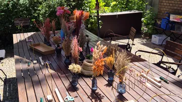 Getrocknete Blumen auf Holztisch draußen arrangiert.
