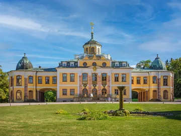 Historisches Gebäude mit Kuppeln, umgeben von grünem Rasen.