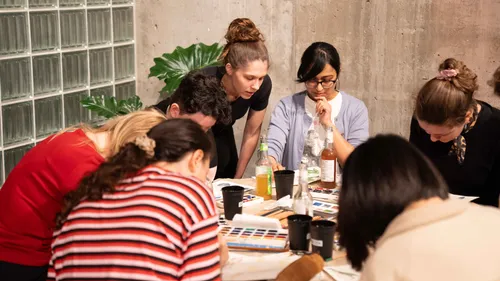 Menschen malen am Tisch, Kunstmaterialien sammeln.