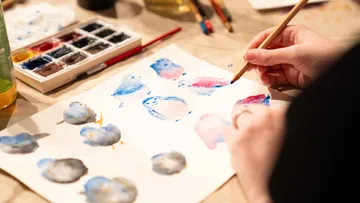 Person malt Vögel mit Aquarellen auf Papier.