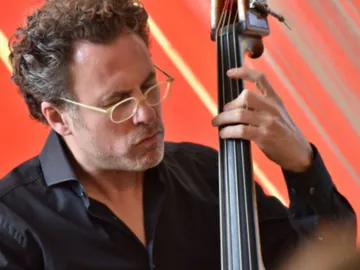 A musician plays double bass against a red background.