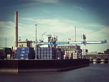 Containers are moved around the port by a crane.