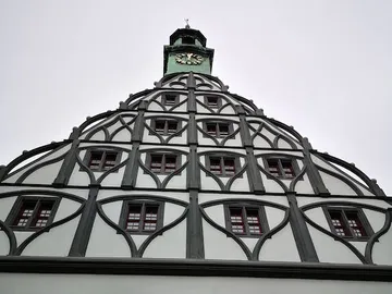 Half-timbered building with curved roof and green clock.