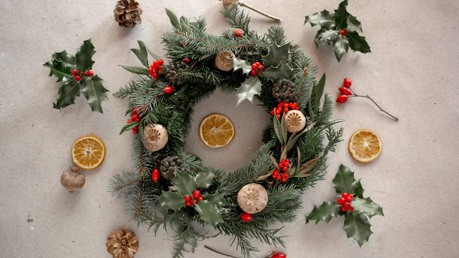 Festive wreath with pinecones on gray background.
