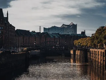 Historische Gebäude spiegeln sich im Wasser unter einer Brücke.