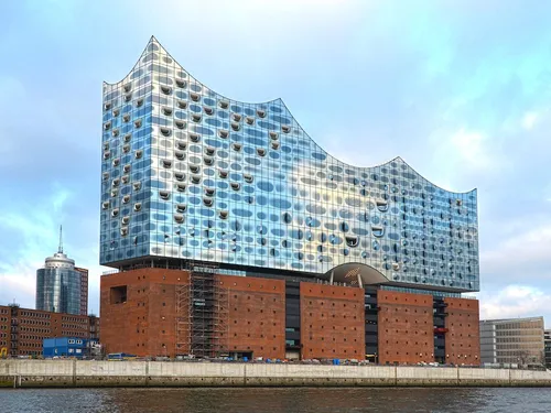 Modern architecture reflects the sky, stands by the water.