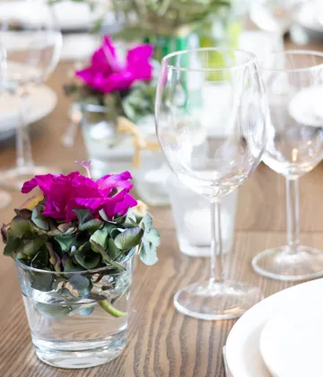 Pinke Blumen im Glas auf Tisch.