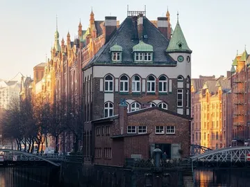 Ein historisches Gebäude steht zwischen Wasser und Straßen.