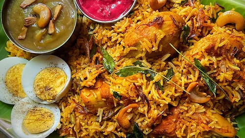 Biryani served on banana leaf with sauces.