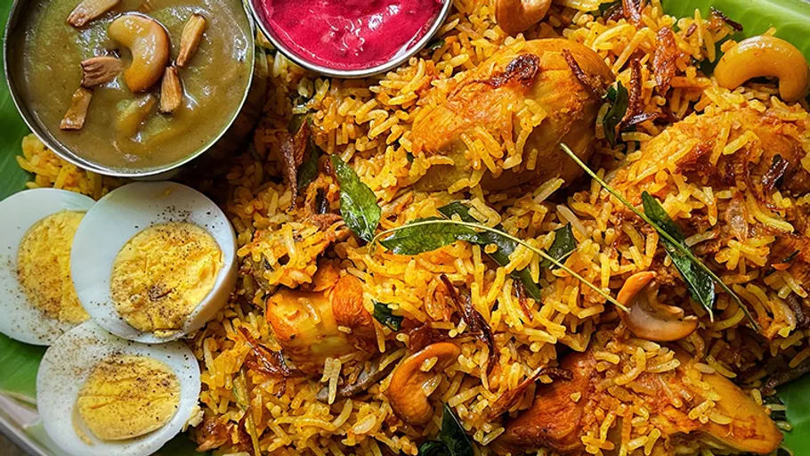Biryani auf Bananenblatt mit Soßen serviert.