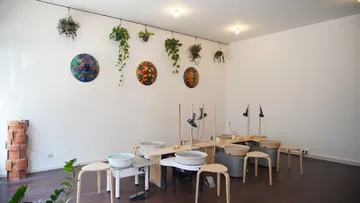 Art studio with pottery wheels and plants.