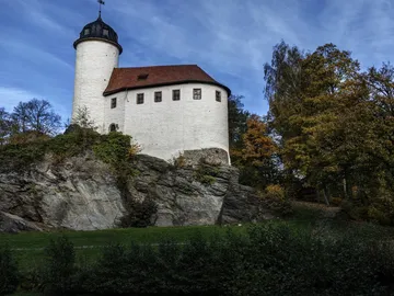 Schloss steht auf einem Felsen, umgeben von Bäumen.