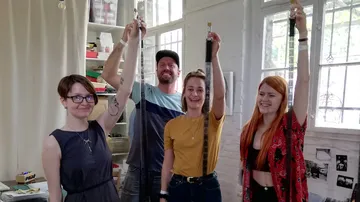 Vier Personen halten lange Filmstreifen drinnen.