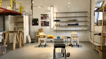 Töpferstudio mit Drehscheiben und Regalen.