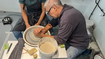 Two people shaping clay on a potter's wheel.
