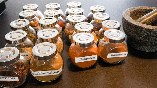 Gewürzgläser auf Theke neben Mörser.
