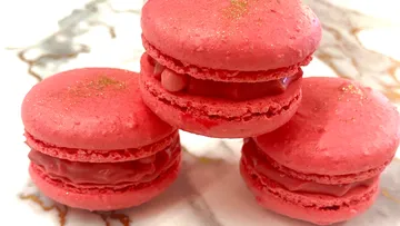 Rote Macarons auf Marmortisch gestapelt.