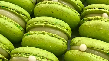 Grüne Macarons mit weißer Füllung eng beisammen.