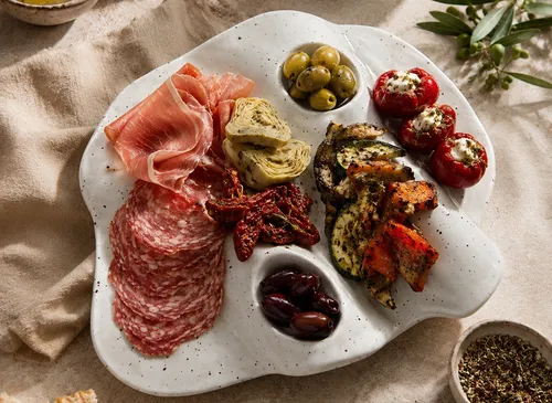 Charcuterie-Platte mit Fleisch, Käse, Gemüse, Kräutern.