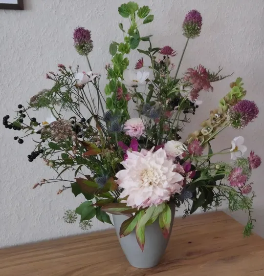 Blumenstrauß in Vase auf Holztisch.