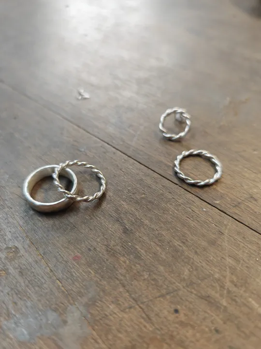 Vier silberne Ringe auf Holztisch.