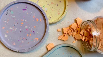 Bunte Terrazzo-Teller neben Gläsern mit Fragmenten.