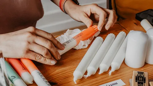 Hands arranging colorful candles on a table.