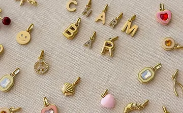 Assorted gold charms on a beige fabric.