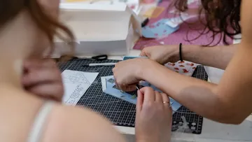 People crafting at a table, focused workspace.