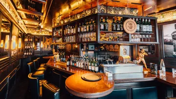 Bar with bottles, glasses, cozy lighting.
