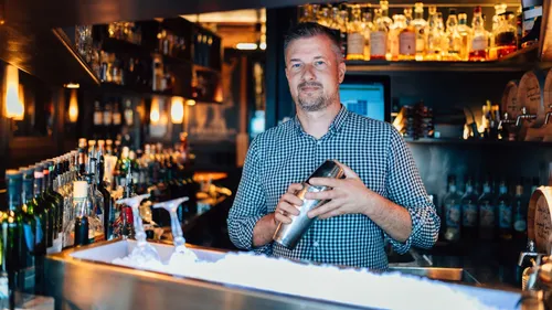 Bartender shaking cocktail in a dimly lit bar.