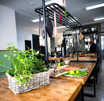 Kitchen counter with vegetables and hanging utensils.