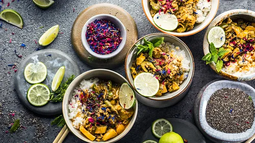 Bowls of curry on a textured grey surface.