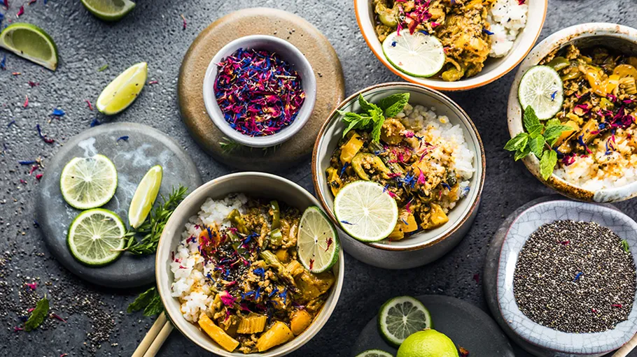 Bowls of curry on a textured grey surface.