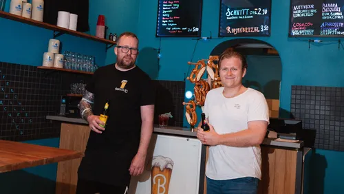 Zwei Männer mit Getränken in einer Bar.
