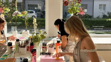 Frauen malen bei einem Kunstworkshop drinnen.
