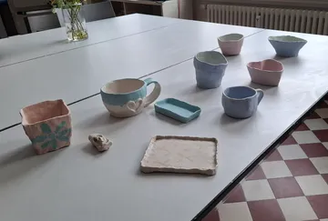 Keramikbecher und Schalen auf Tisch.