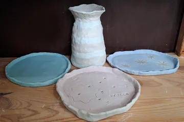 Clay ceramics displayed on a wooden table.